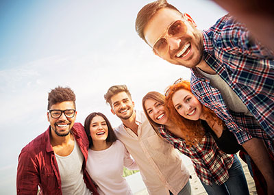 A group of young adults posing together for a selfie, smiling and enjoying their time outdoors.